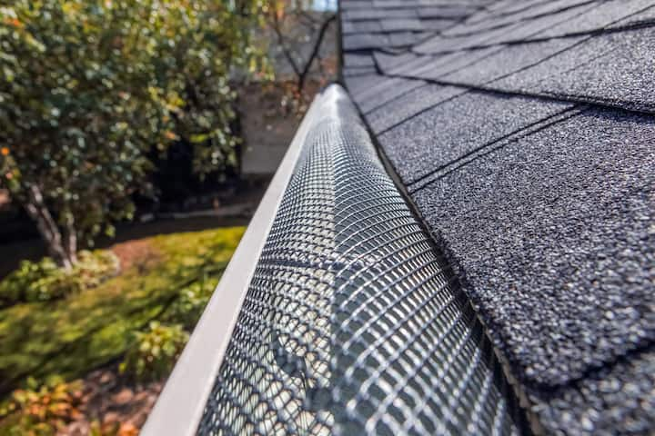 A contractor demonstrating the effectiveness of a gutter guard to a potential client in Greenville